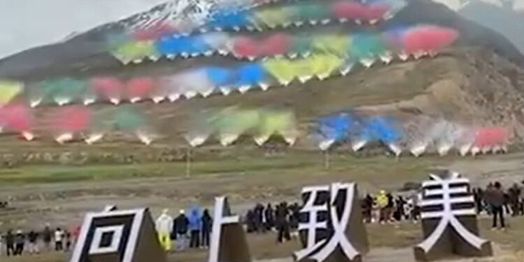 Se exhiben fuegos artificiales con múltiples columnas de humo coloridas en una montaña, sobre grandes caracteres chinos blancos.