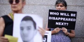 Una mujer tiene un letrero que lee "¿Quién desaparecerá a continuación?" A medida que los manifestantes se reúnen fuera de la misión permanente de El Salvador ante las Naciones Unidas en Nueva York para leer los nombres de los detenidos en Cecot, la prisión de máxima seguridad de El Salvador, el 5 de junio de 2025.