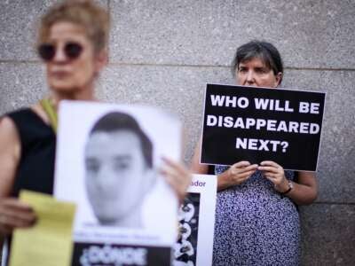 Una mujer tiene un letrero que lee "¿Quién desaparecerá a continuación?" A medida que los manifestantes se reúnen fuera de la misión permanente de El Salvador ante las Naciones Unidas en Nueva York para leer los nombres de los detenidos en Cecot, la prisión de máxima seguridad de El Salvador, el 5 de junio de 2025.