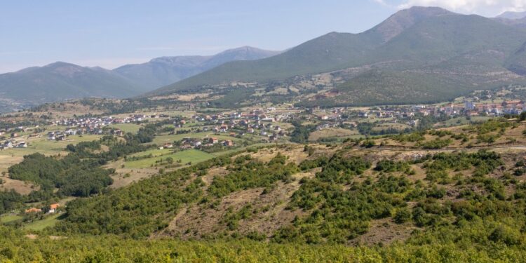 La ciudad de Golaj en el norte de Albania, con villas construidas y rodeadas de montañas y árboles.
