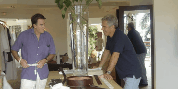 Dos hombres mirando los cinturones en una tienda.