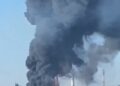 Grandes columnas de humo negro y fuego se elevan de una planta industrial.