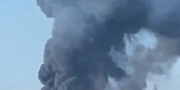 Grandes columnas de humo negro y fuego se elevan de una planta industrial.