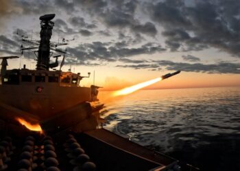 Una fragata disparando un misil sobre el océano al atardecer.