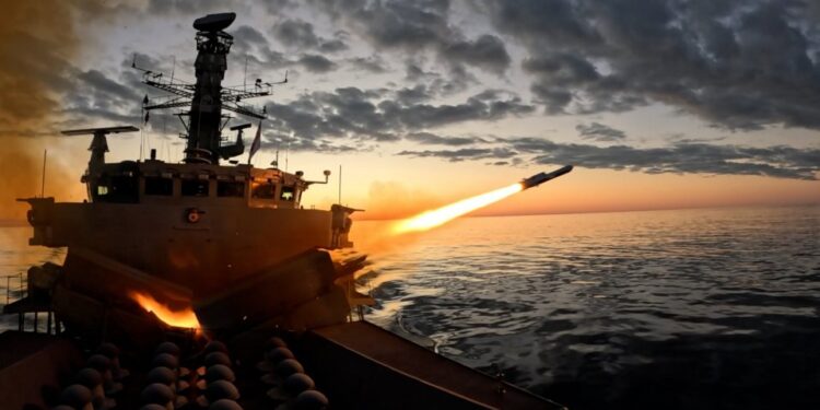 Una fragata disparando un misil sobre el océano al atardecer.