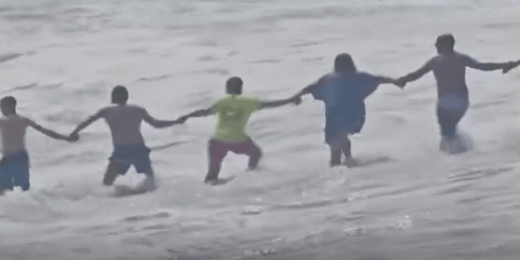 Cadena humana rescatando a un niño de fuertes corrientes.