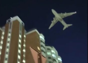 Un gran avión militar volando bajo sobre edificios residenciales en Moscú por la noche.