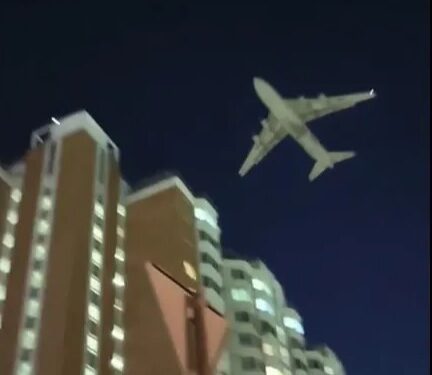 Un gran avión militar volando bajo sobre edificios residenciales en Moscú por la noche.