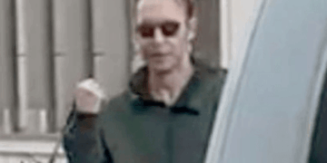 Hombre con gafas de sol y una sudadera oscura, con su mano izquierda apretada.