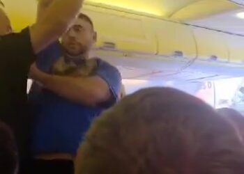 Los oficiales de policía retiran a un pasajero disruptivo de un avión.