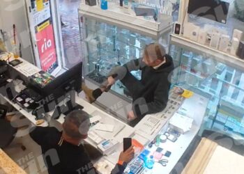 Christian Bruckner mostrando su etiqueta de tobillo al dueño de una tienda en Neumünster, Alemania.