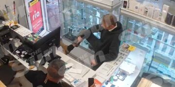 Christian Bruckner mostrando su etiqueta de tobillo al dueño de una tienda en Neumünster, Alemania.