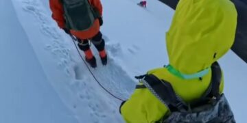 Los excursionistas en una cresta de montaña nevada con un pico en el fondo.