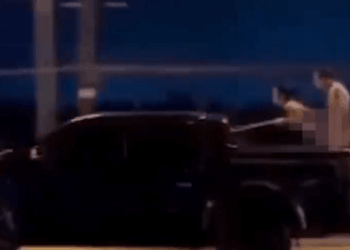 Dos personas con cuerpos borrosos en la cama de un camión en movimiento.