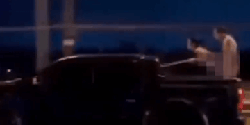 Dos personas con cuerpos borrosos en la cama de un camión en movimiento.