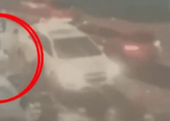 Foto borrosa y granulada de tres figuras entrando en un automóvil, resaltada por un círculo rojo.