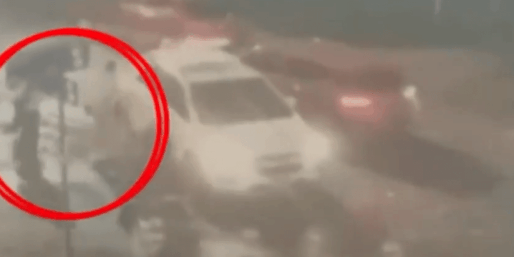 Foto borrosa y granulada de tres figuras entrando en un automóvil, resaltada por un círculo rojo.