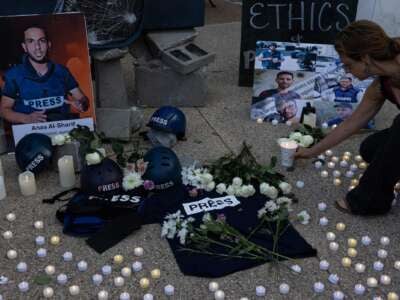 La gente sostiene fotos, pone flores y velas ligeras durante una vigilia fuera de la sede de Fox News y NBC News en Washington, DC, el 11 de agosto de 2025, en honor a periodistas asesinados en Gaza, incluidos Anas al-Sharif y sus colegas.