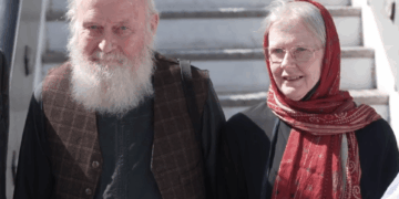 Un hombre calvo con barba blanca y una mujer con un pañuelo rojo.