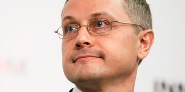 Molchado de la cabeza de Alexander Tyunin, un hombre con cabello gris corto, con un traje azul y una corbata rosa.