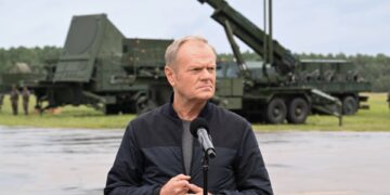 El primer ministro Donald Tusk habla en un podio frente a los vehículos militares durante el ejercicio de entrenamiento 'Autumn Fire-25'.