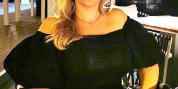 Mujer sentada en una mesa de restaurantes al aire libre.