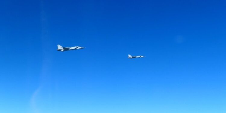 Dos aviones de combate MIG-31 rusos volando en cielos azules claros.