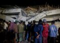 Parientes parados frente a un edificio colapsado durante una operación de rescate en un internado islámico.
