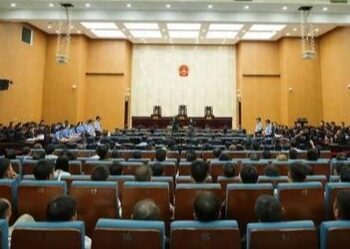 Personas paradas en una sala del tribunal, con una mezcla de acusados y policías.