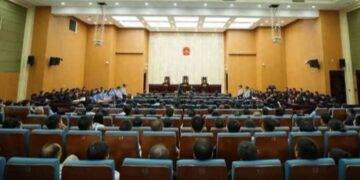 Personas paradas en una sala del tribunal, con una mezcla de acusados y policías.