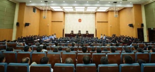 Personas paradas en una sala del tribunal, con una mezcla de acusados y policías.