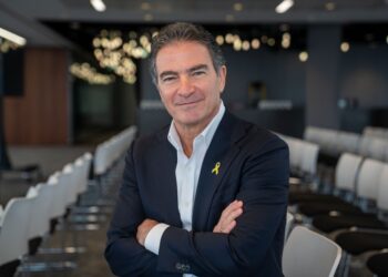 Yossi Cohen, ex jefe de Mossad, sonriendo con los brazos cruzados, con un traje con un alfiler amarillo.