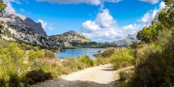 Camino que conduce a un lago rodeado de montañas.