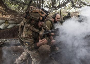Dos soldados ucranianos con una pistola de artillería están envueltas en humo.
