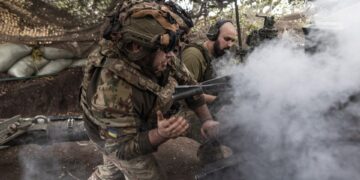 Dos soldados ucranianos con una pistola de artillería están envueltas en humo.