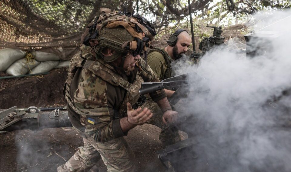 Dos soldados ucranianos con una pistola de artillería están envueltas en humo.