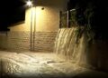 Las aguas nocturnas en cascada sobre una pared en una calle, iluminadas por una luz de la calle.