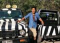 Zookeeper parado entre dos jeeps de safari rallados en cebra.