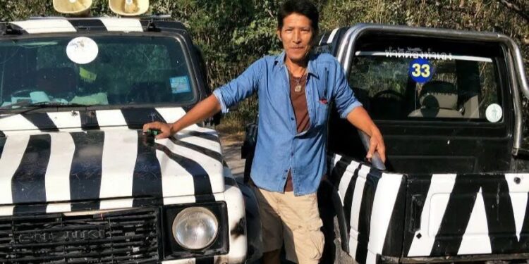 Zookeeper parado entre dos jeeps de safari rallados en cebra.