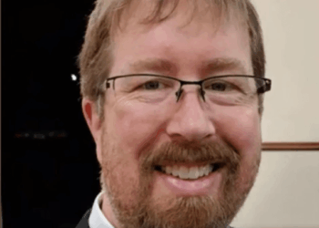 Tiro en la cabeza de un hombre sonriente con gafas y barba.