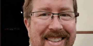 Tiro en la cabeza de un hombre sonriente con gafas y barba.