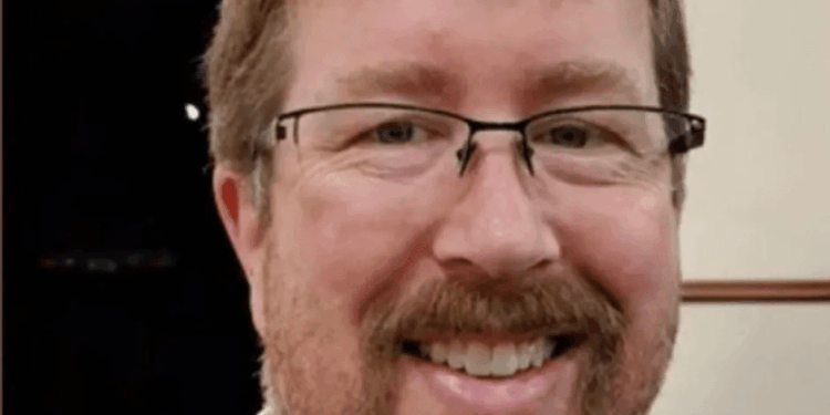 Tiro en la cabeza de un hombre sonriente con gafas y barba.