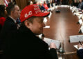 Elon Musk, con un sombrero rojo, observa mientras el presidente Donald Trump organiza una reunión de gabinete en la Sala del Gabinete de la Casa Blanca el 24 de marzo de 2025, en Washington, DC.