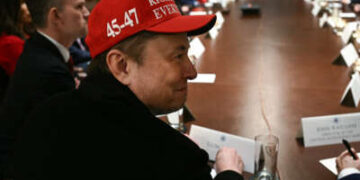 Elon Musk, con un sombrero rojo, observa mientras el presidente Donald Trump organiza una reunión de gabinete en la Sala del Gabinete de la Casa Blanca el 24 de marzo de 2025, en Washington, DC.