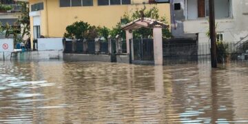 Edificios y una puerta parcialmente sumergida por aguas de inundación.
