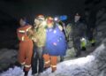 Los rescatadores en la nieve ayudan a un excursionista varado por la noche con faros.