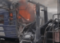 El vagón de tren dañado envuelto en llamas y humo.