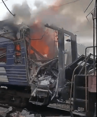 El vagón de tren dañado envuelto en llamas y humo.