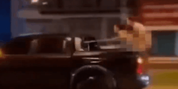 Una persona en la parte trasera de una camioneta en movimiento apunta a una pistola.