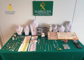 Joyas robadas y efectivo recuperados por la policía, colocados sobre una tela verde.